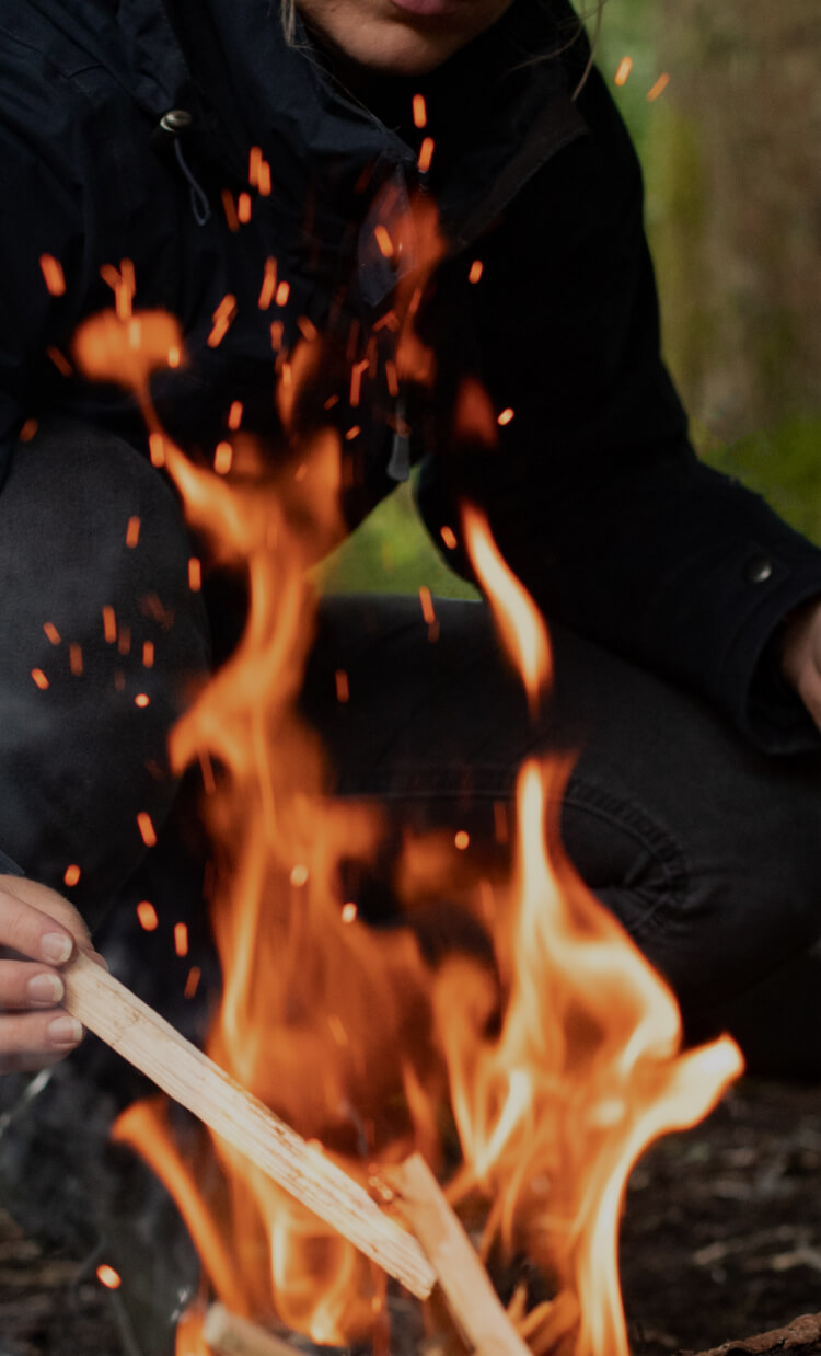 Man throwing sticks into the bonfire 