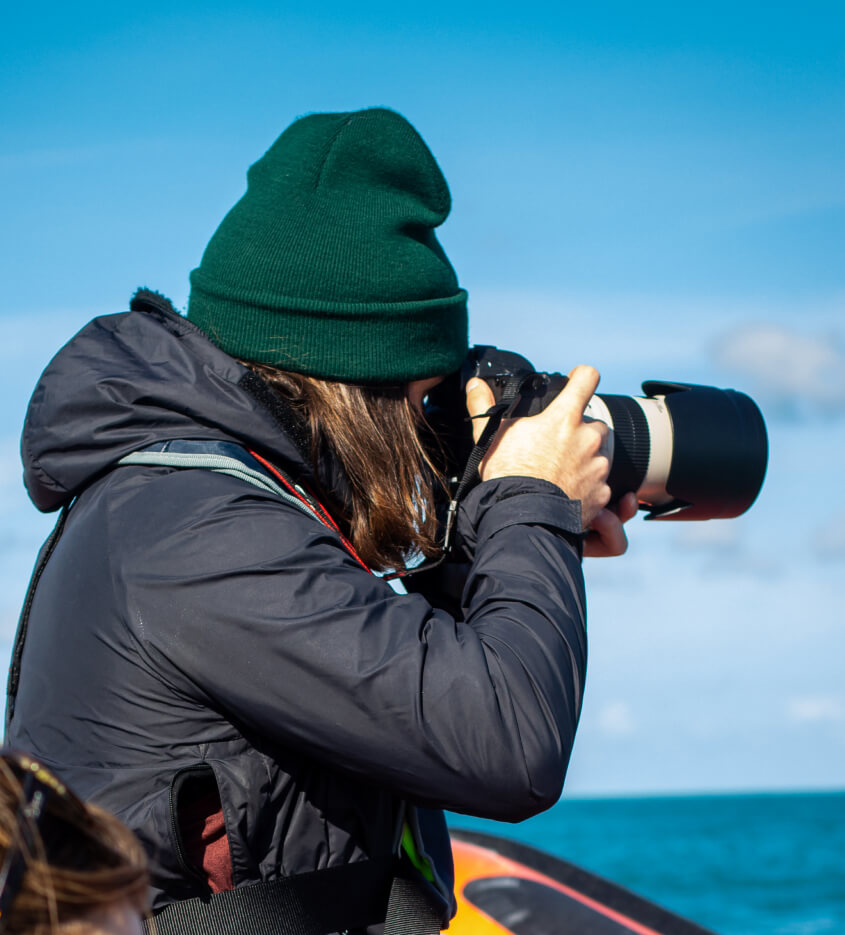 Woman in a boat taking a photo of the ocean