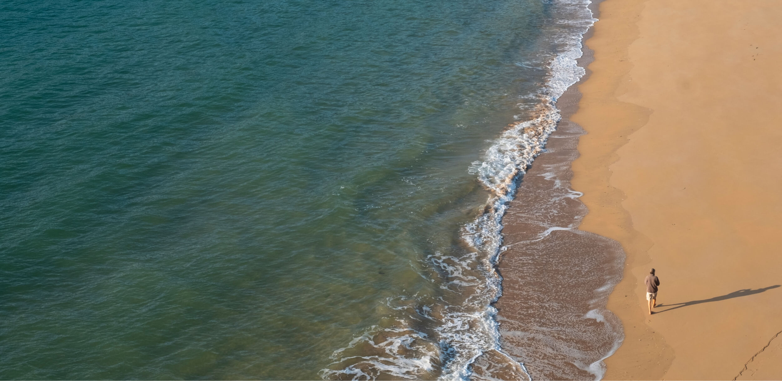 Person running on the shore of the calm ocean