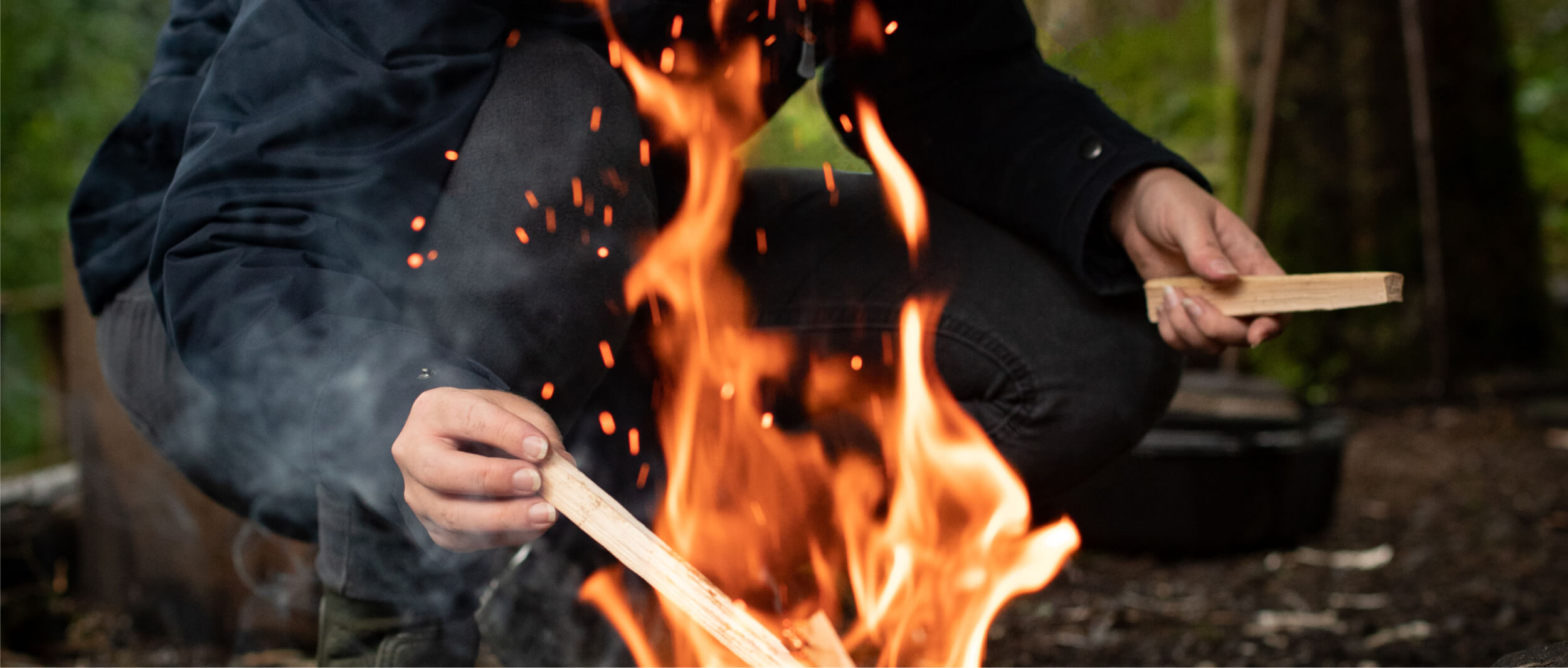 Man throwing sticks into the bonfire 